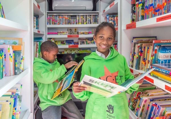 Two children reading books in a FACET mobile reading library