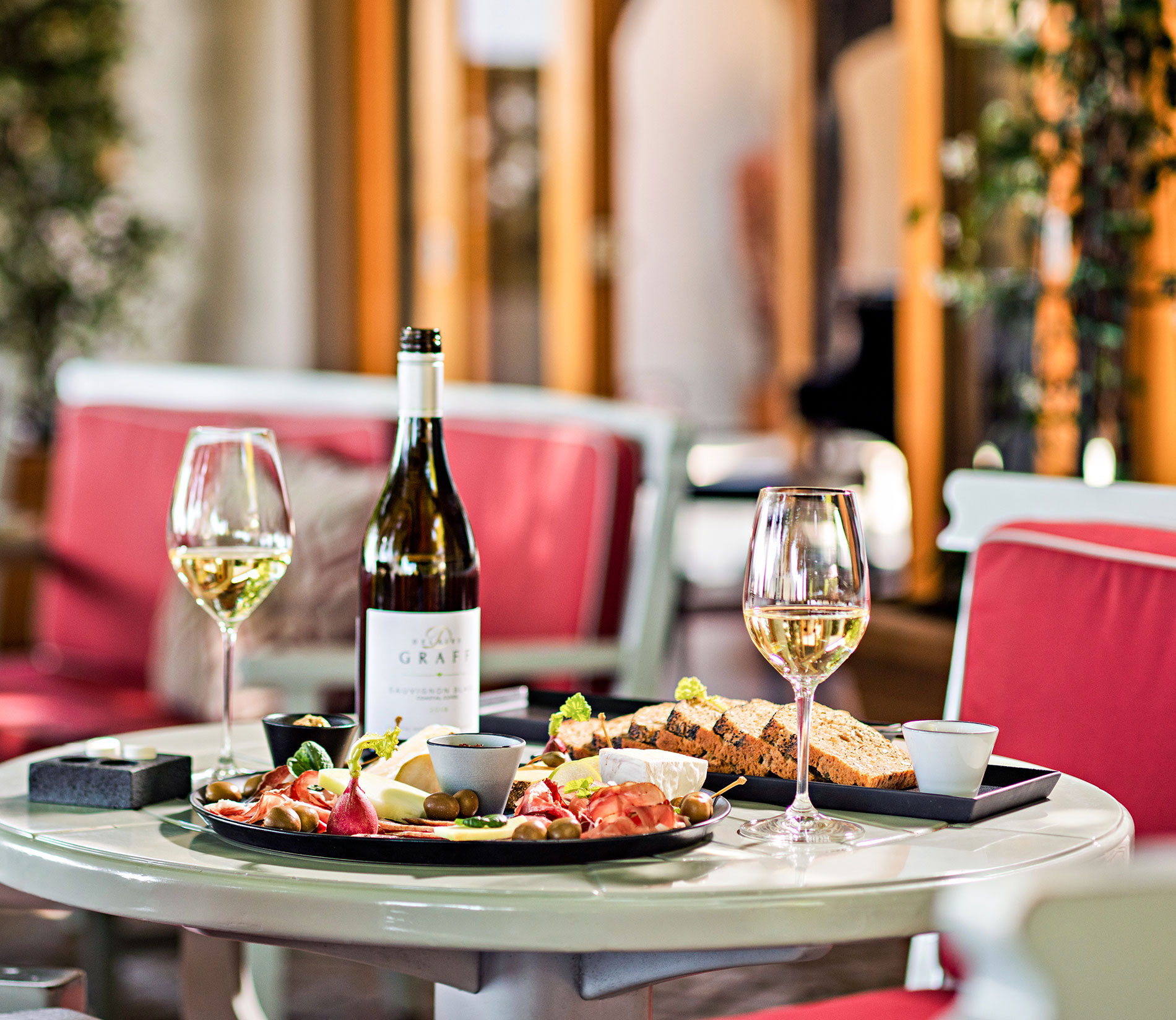 A dining table with wine and a sharing food platter in the Wine Lounge at Delaire Graff Estate