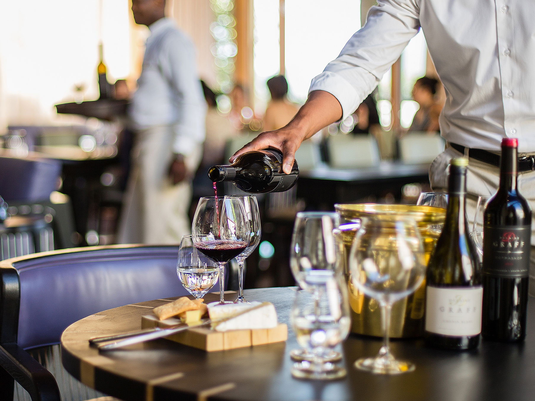 A waiter pouring red wine at Delaire Graff Estate wine lounge