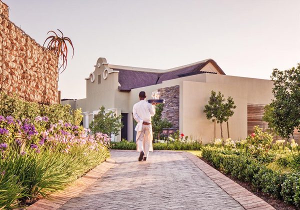 A waiter delivering wine to a Lodge at Delaire Graff Estate