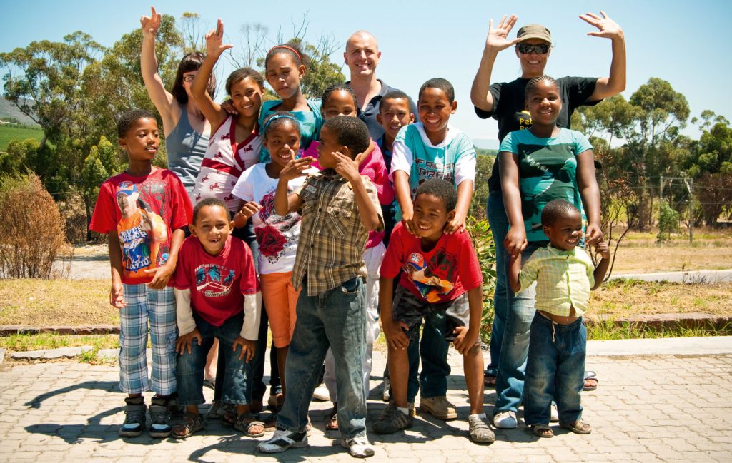 A group of smiling children and their teachers outside a Graff Leadership Centre